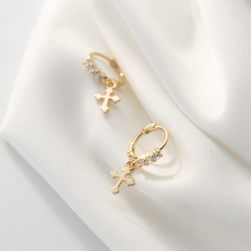 Glossy Cross Earrings hanging on soft fabric showcasing their polished design and elegant finish.