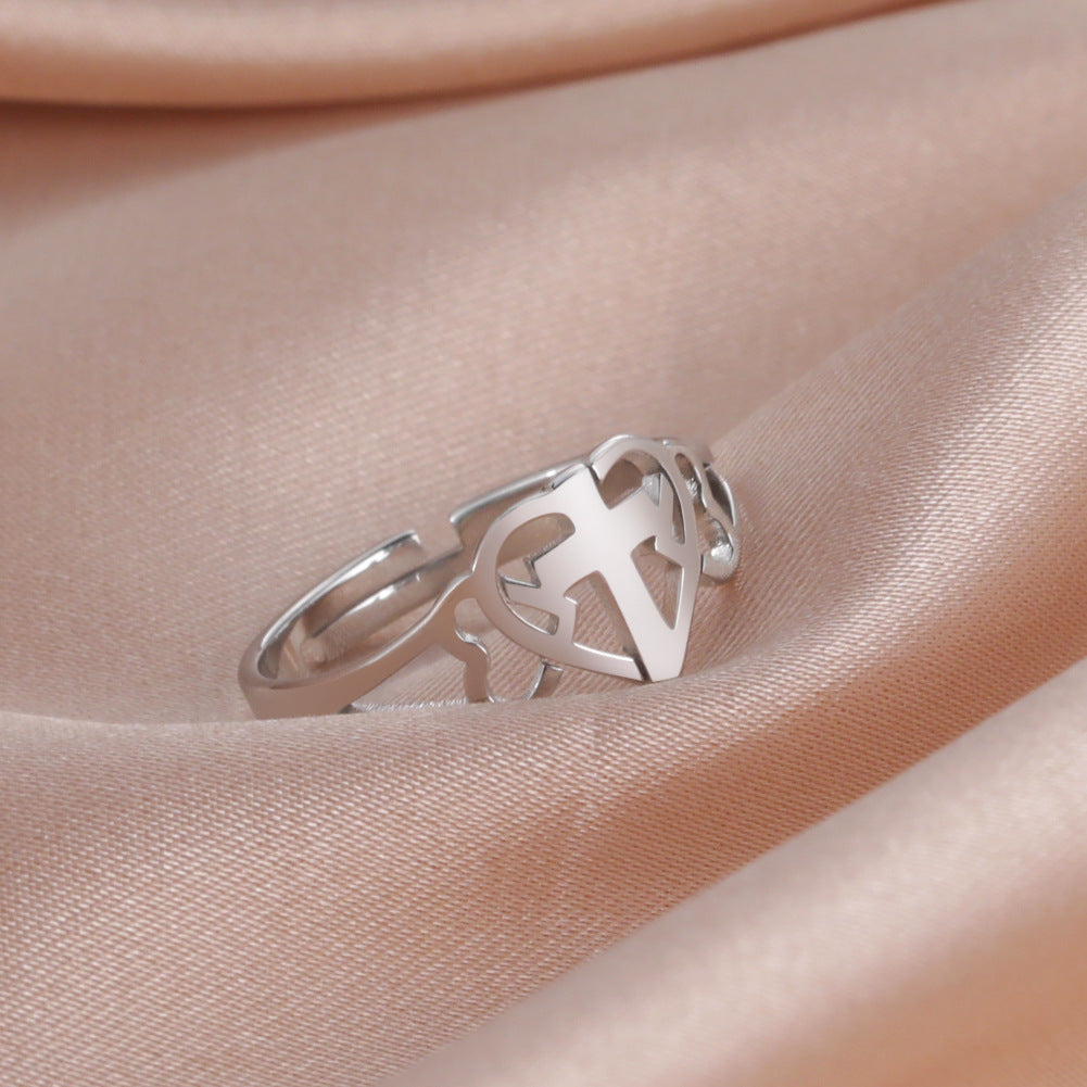 Stainless Steel Love Cross Ring displayed on soft satin fabric, featuring a minimalist design with a cross and heart symbol.
