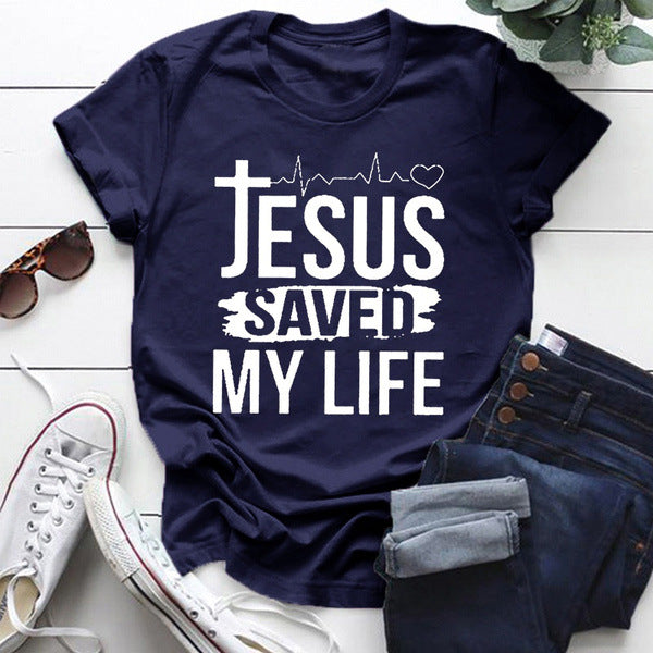 Jesus Saved My Life Short Sleeve T-shirt displayed on a wooden surface with stylish accessories.