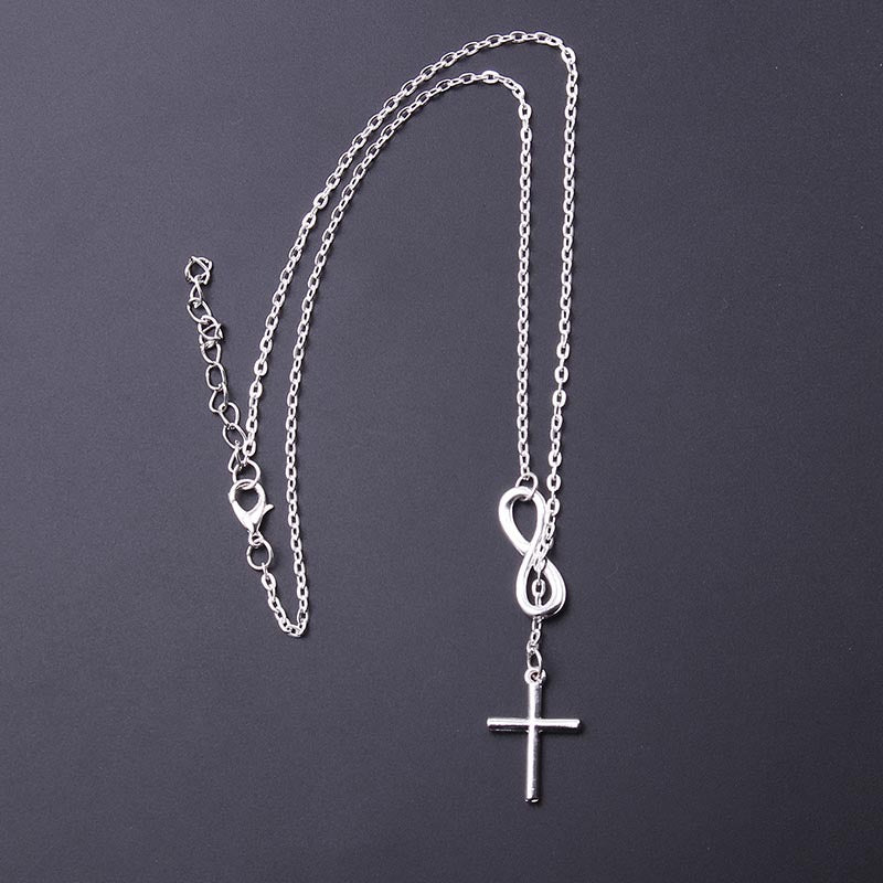 Hollow Cross Clavicle Necklace hanging on a dark background, featuring a minimalist stainless steel cross pendant.